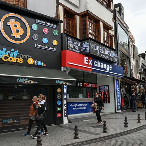 People pass by a cryptocurrency exchange branch near the Grand Bazaar in Istanbul on Oct. 20, 2021, a day after Bitcoin took another step closer to mainstream investing with the launch of a new security on Wall Street tied to futures of the cryptocurrency. 