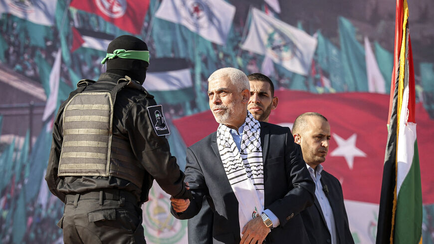 Yahya al-Sinwar (C), Gaza Strip chief of the Palestinian Islamist Hamas movement, shakes hands with a masked fighter of Hamas' Qassam Brigades during a rally marking the 35th anniversary of the group's foundation, in Gaza City on December 14, 2022. Hamas will end talks on securing a prisoner exchange with Israel unless there is progress soon, the militant group's leader in the Gaza Strip said on December 14. Since Israel's 2014 invasion of the Gaza Strip, the Islamist group has held the bodies of Israeli so