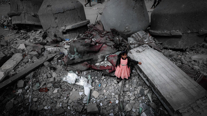 TOPSHOT - A Palestinian girl wearing a pink dress stands amidst the ruins of the Al-Faruq Mosque that was destroyed during Israeli bombardment, in Rafah on the southern Gaza Strip on March 22, 2024, amid ongoing battles between Israel and the militant group Hamas (Photo by MOHAMMED ABED / AFP) (Photo by MOHAMMED ABED/AFP via Getty Images)