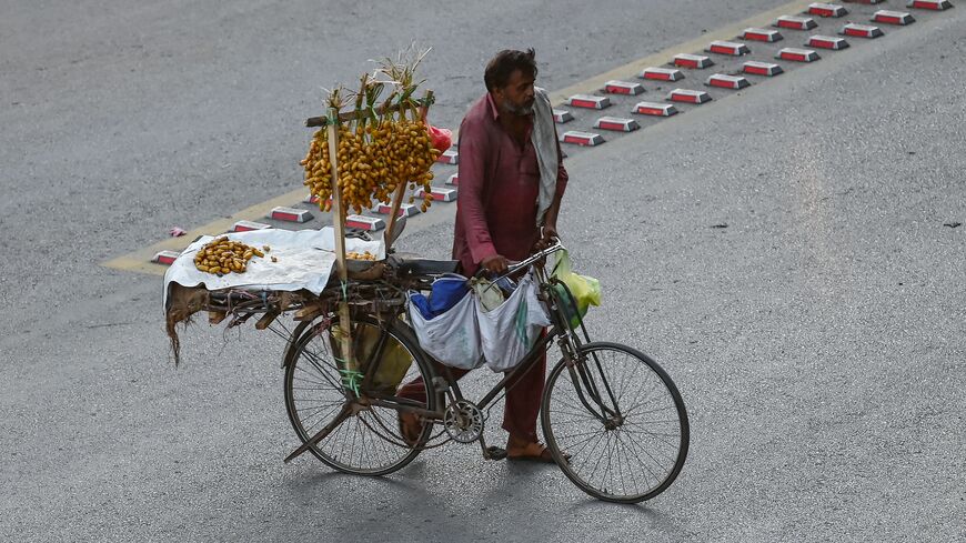 A vendor selling dates walks across a street in Islamabad on July 8, 2024, as cash-strapped Pakistan adopted a $68 billion budget laced with tax-raising measures on June 28, seeking to secure a new bailout from the IMF.