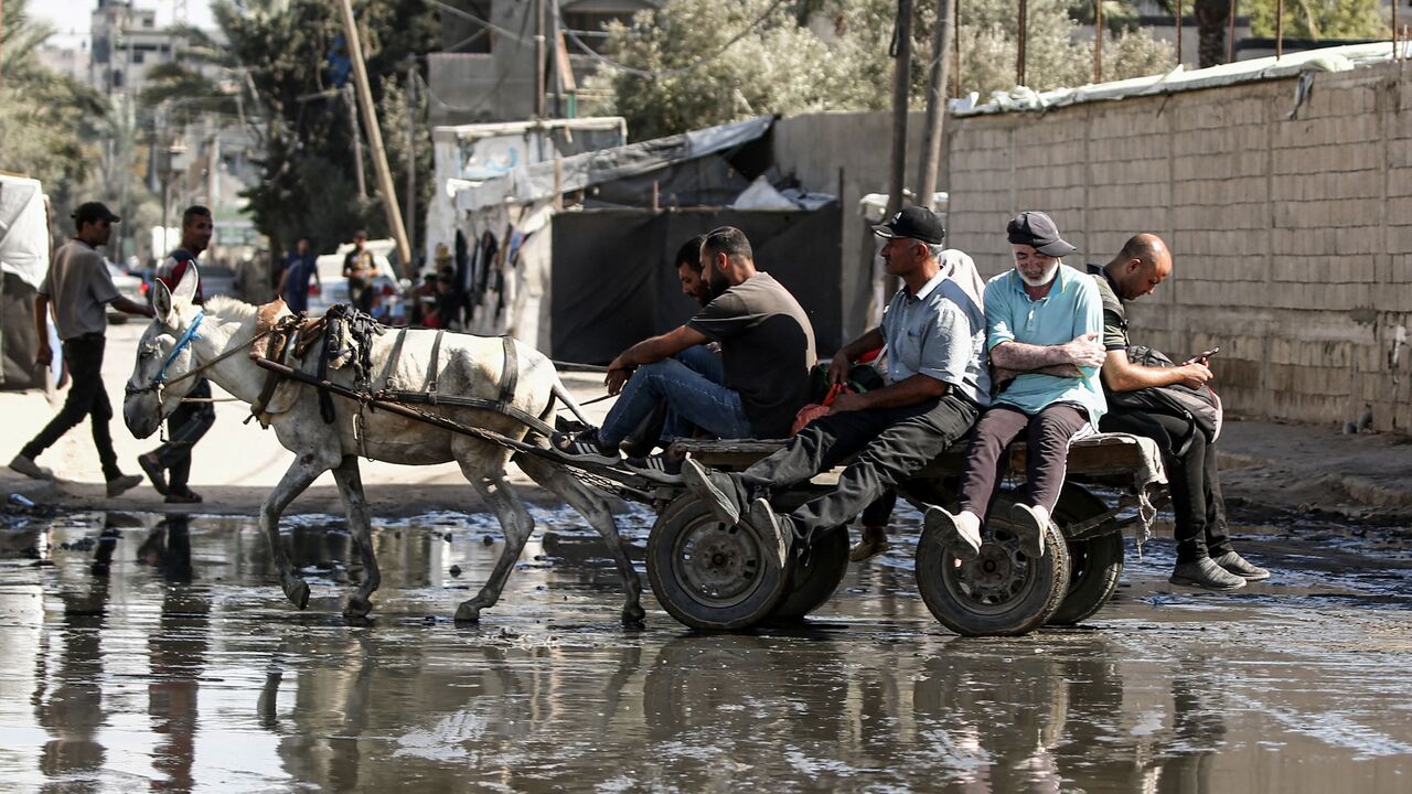 Displaced people ride on a donkey-drawn cart through a muddy puddle in Deir al-Balah in the central Gaza Strip on Sept. 30, 2024.