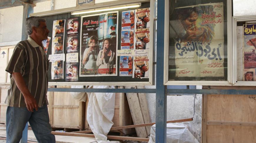 A resident walks at the entrance of a cinema in Baghdad April 26, 2011. Iraq once had 82 cinemas, 64 of them located in the teeming capital, home to about 7 million of Iraq's 30 million people. One by one, they closed during the Saddam era, when the government controlled the selection and importation of films, until only five remained at the time of the invasion. The insurgency that followed and killed tens of thousands of people made Iraqis afraid of being in public places and crowds. They chose the relati