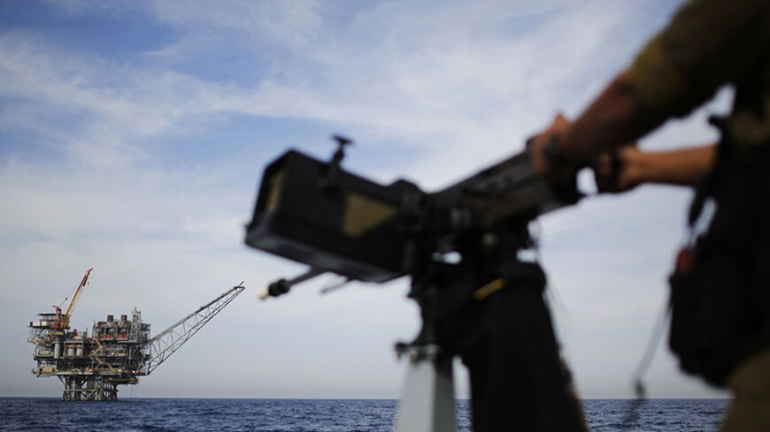 An Israeli gas platform is seen in the back as a sailor in the Israeli navy stands aboard a patrol boat in the Mediterranean sea some 15 miles (24 km) west of the port city of Ashdod February 25, 2013. Israel's huge new offshore gas resource offers its enemies an obvious target and gives its navy, long overshadowed by other branches of the Israeli armed forces, a big job that will require extra spending. Picture taken February 25, 2013. REUTERS/Amir Cohen (ISRAEL - Tags: MILITARY ENERGY BUSINESS POLITICS MA